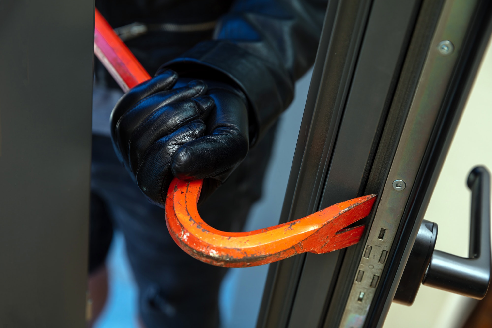 Housebreaker holding a crowbar to break a glass window.